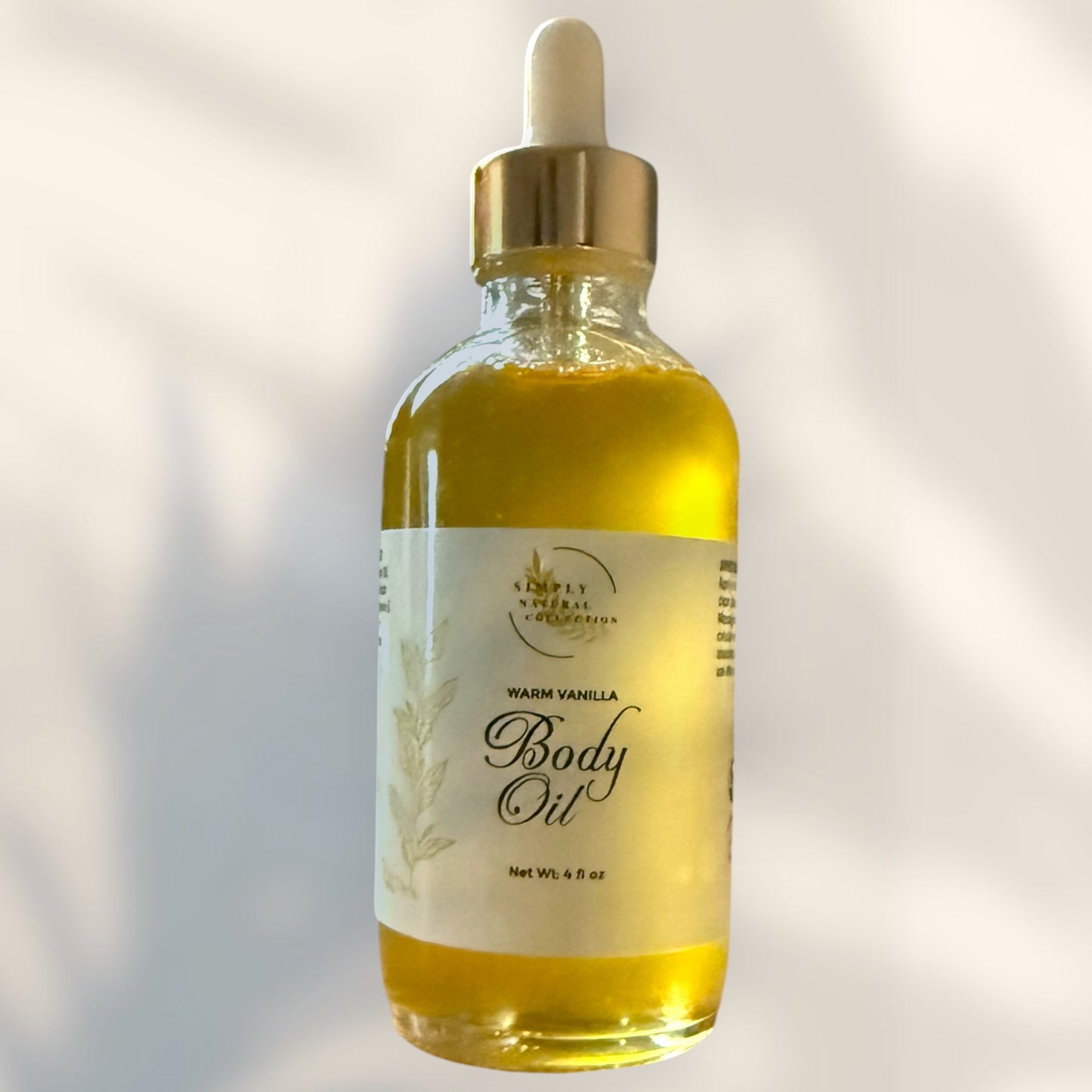 Bottle of warm vanilla body oil with dropper on a light background