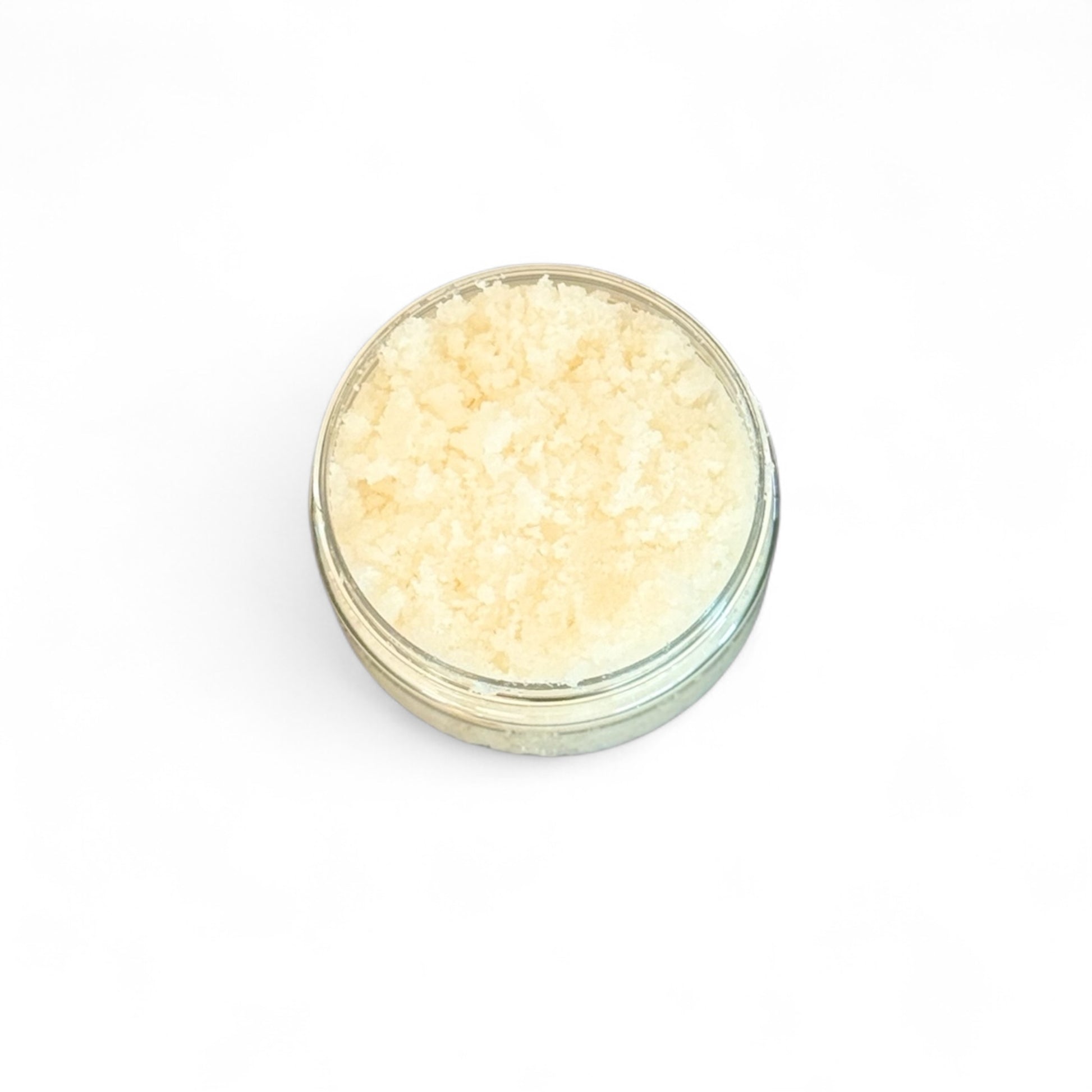 Small glass jar filled with light-colored Peaches and cream body scrub  on a white background