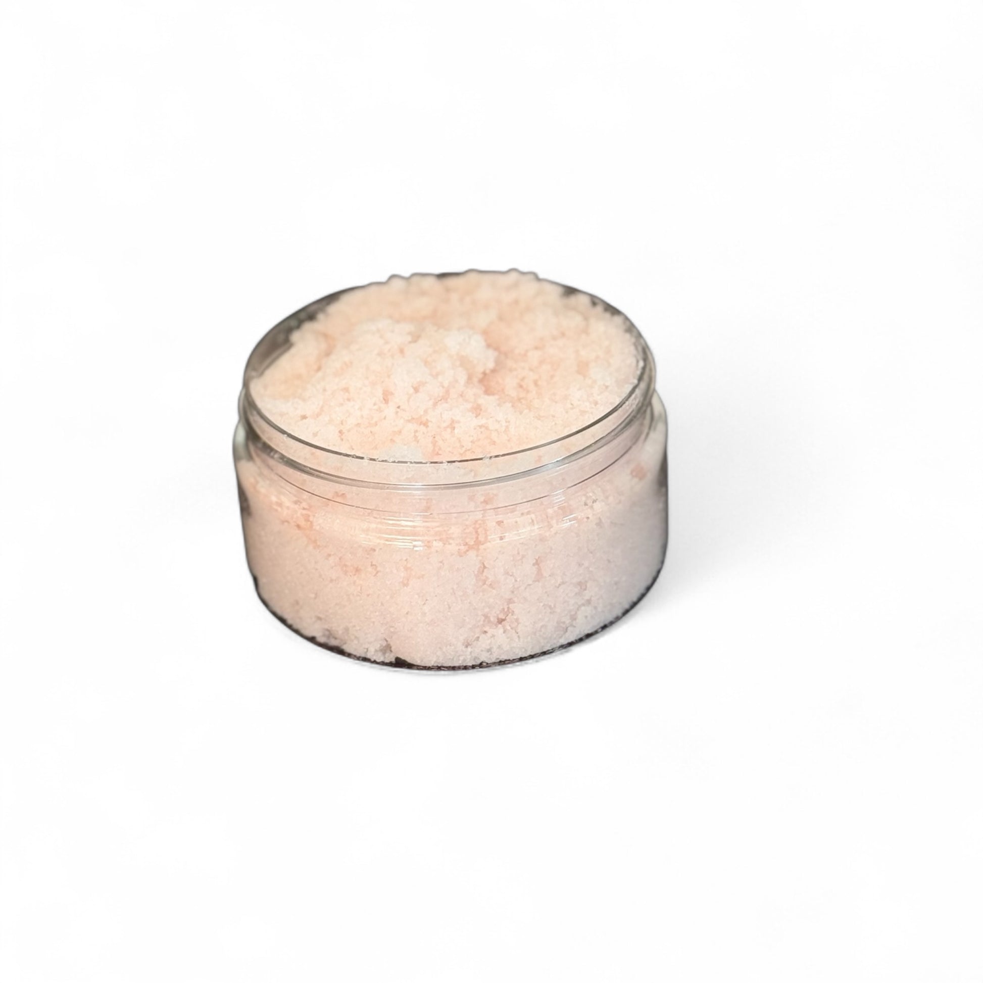 Clear container filled with pink body sugar scrub on a white background