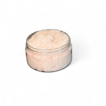Clear container filled with pink body sugar scrub on a white background