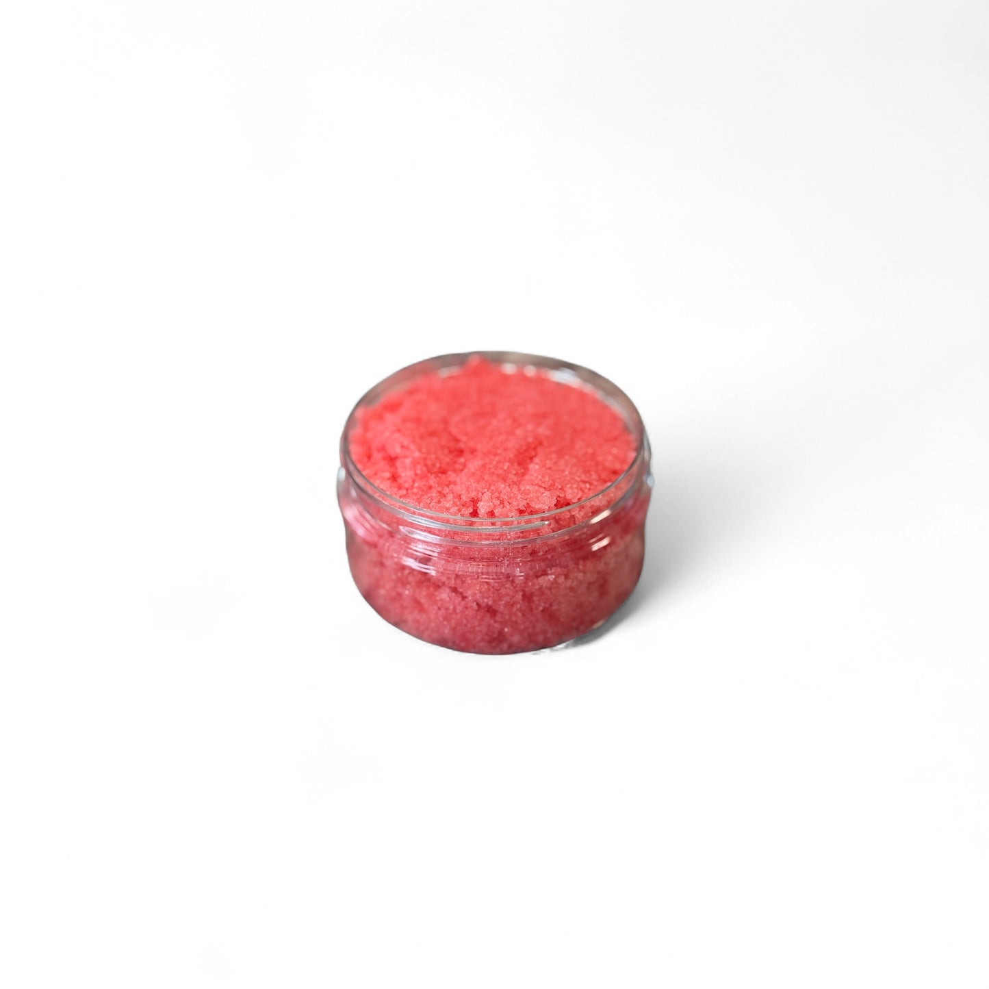 Small clear container filled with strawberry cream body scrub on a white background